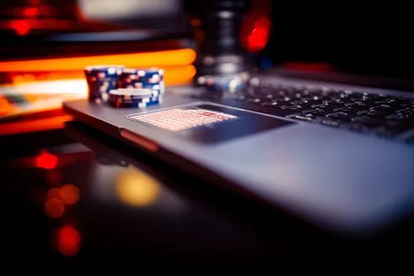 A woman smiling while playing online games on her laptop, surrounded by neon casino elements, showcasing KOKOZINO’s diverse game collection.