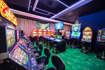 A man celebrating a winning moment on his laptop while gaming symbols float around him, capturing the excitement of KOKOZINO games.